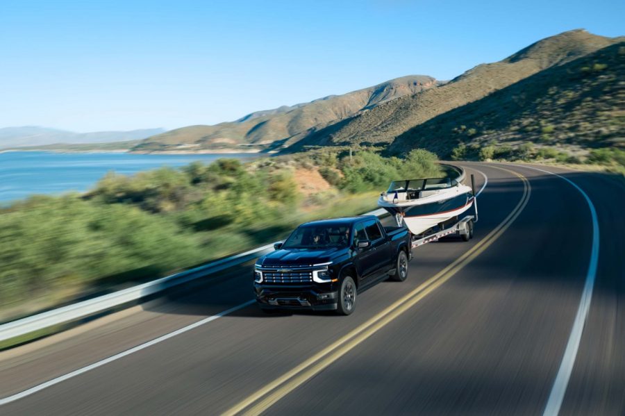2027 Chevrolet Silverado Truck towing a boat near a lake.
