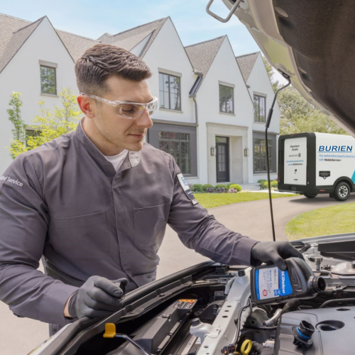 Burien Chevrolet Mobile Service technician performing an oil change at a customer's home with the Burien Chevrolet service van in the background
