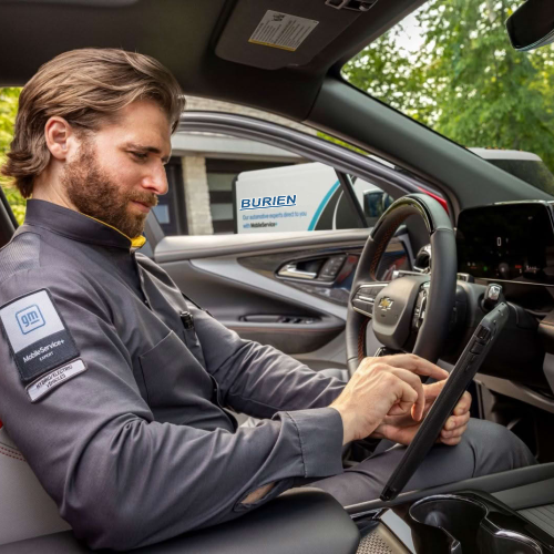 Burien Chevrolet Mobile Service technician performing a GM diagnostic scan using a tablet inside a Chevrolet vehicle